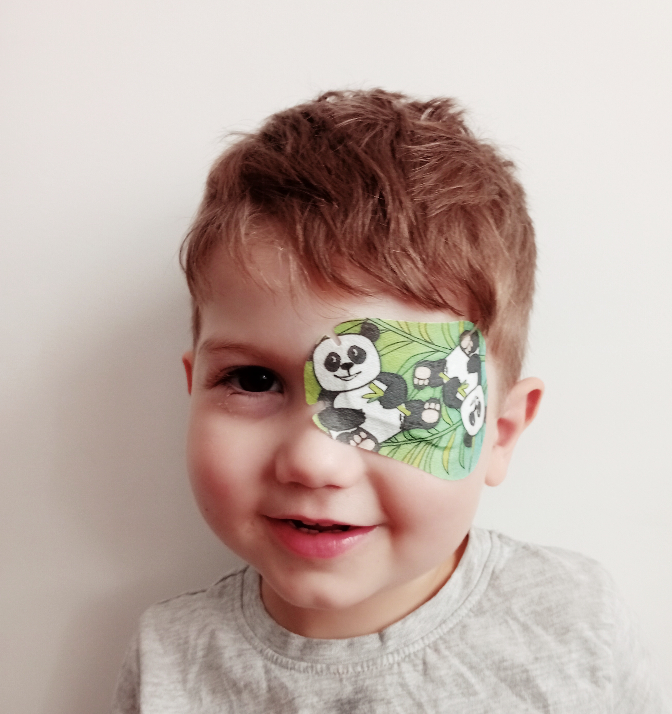 child wearing green eye patch with pandas on it 