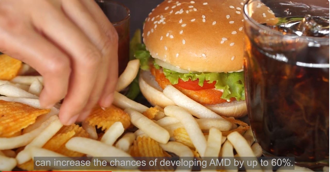 Impact of Diet on AMD Hand in food taking a chip from a burger and chips plate.